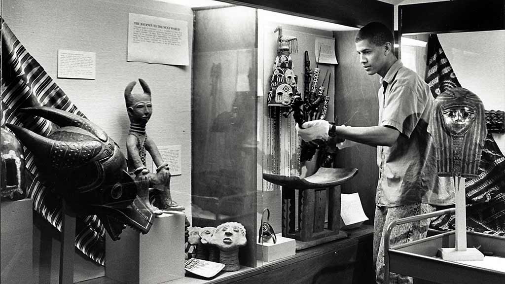 a man installs African objects in a display case