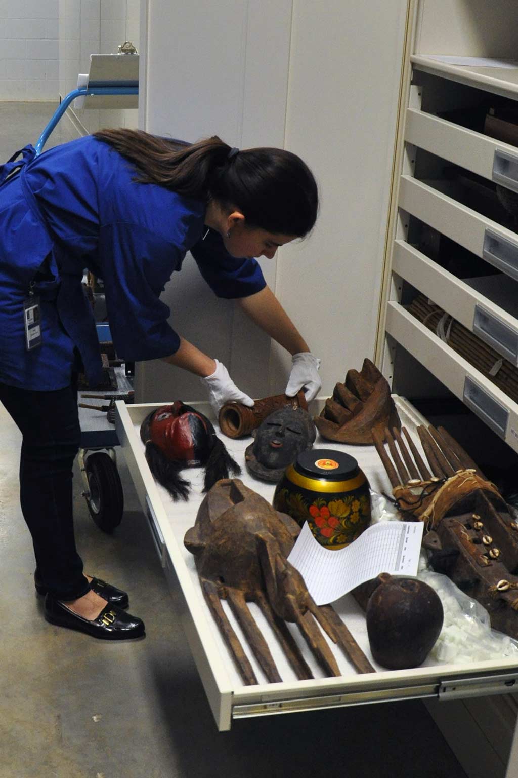 Preservation assistant working with artifacts in a storage drawer