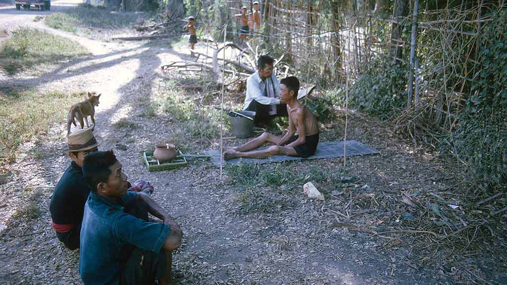 four men sit along the roadside