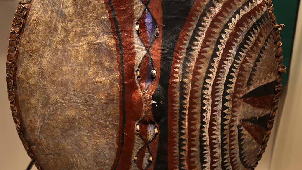 closeup of shield with red and brown geometric design on one half