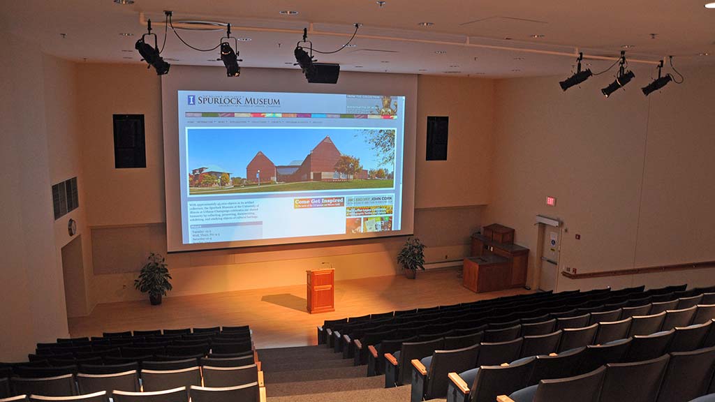 auditorium overview photo with seating, stage, podium, and spotlights